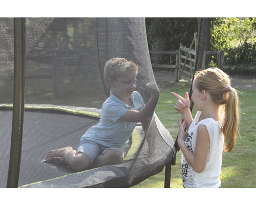 Två barn leker på en studsmatta med säkerhetsnät