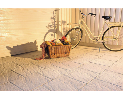 Uteplats med gatsten, cykel och picknickkorg.