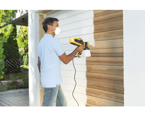 Man lackerar trävägg med färgspraysystem