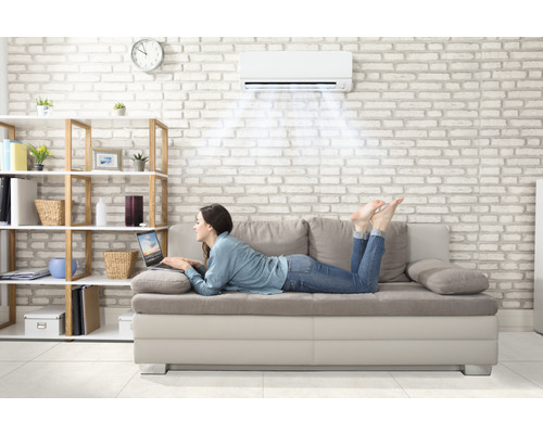 Kvinna ligger på soffan under luftkonditioneringen med en bärbar dator