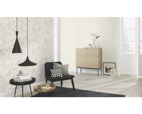 Vardagsrum med mönstrad tapet, svart fåtölj och två hänglampor