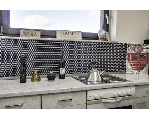 Köksscen med diskho, spis, blandare och köksredskap mot en svart mosaikbakgrund