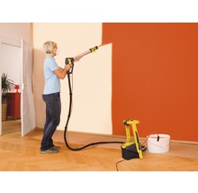 Kvinna använder färgspraysystem för att måla en vägg