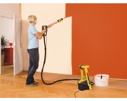 Kvinna använder färgspraysystem för att måla en vägg