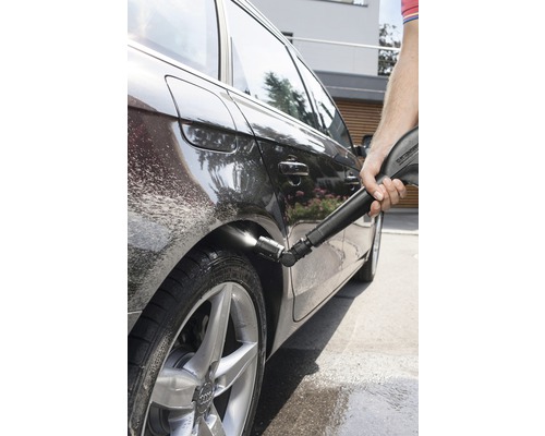 En person rengör en bil med en högtryckstvätt.