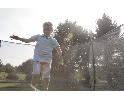 Ett barn hoppar på en studdsmatta med säkerhetsnät.