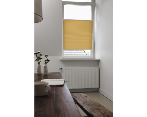 Gul plisségardin vid fönstret i ett ljust rum.