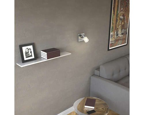 Vardagsrum med vägghylla, bild, bok, väggspotlight och soffa.