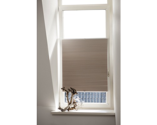 Beige plisségardin vid fönstret för solskydd och dekoration