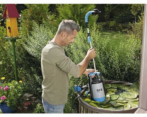 En man använder en dammsugare av märket for.q i en trädgårdsdamm