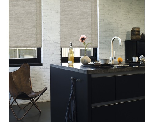 Scen av ett ljust kök med rullgardiner för fönstren, en köksö och en läderfåtölj