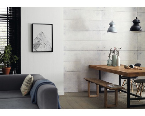 Vardagsrum med soffa, matbord, bänk och väggpaneler i betonglook.