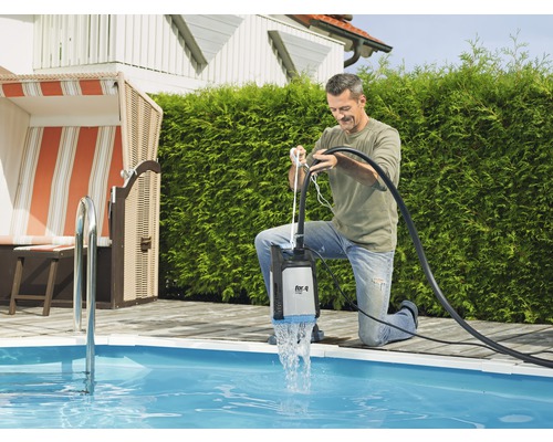 Man använder en dränkpump vid poolen för att tömma vatten.