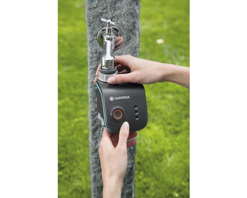 En person fäster en Gardena Smart Water Control bevattningsdator på en utomhuskran.