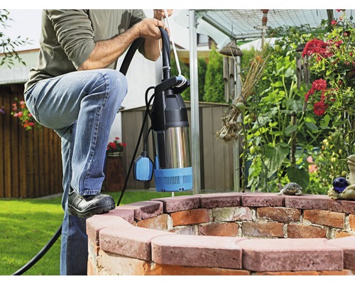 Man med dränkbar pump i en trädgårdsbrunn