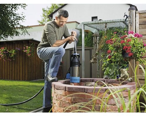 Man använder en djupbrunnspump vid en brunn i trädgården.