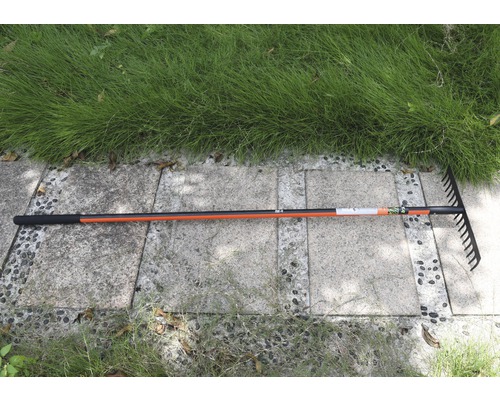 Trädgårdsräfsa med skaft på stenläggning