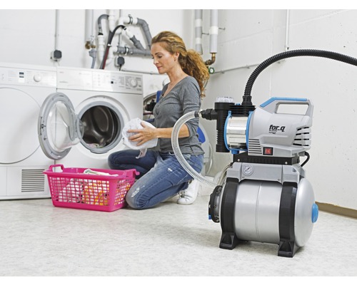 Hydroforpump bredvid tvättmaskin och tvättkorg i en tvättstuga