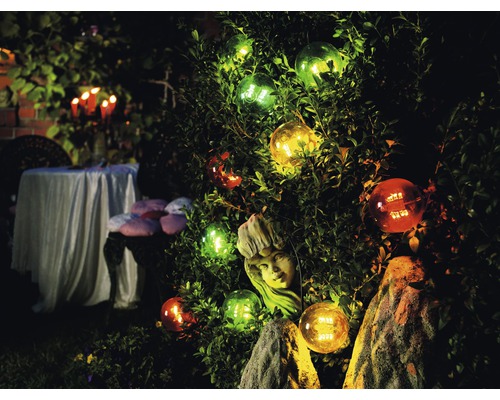 Upplyst trädgård med sfäriska lampor, växter och bordsdekoration utomhus