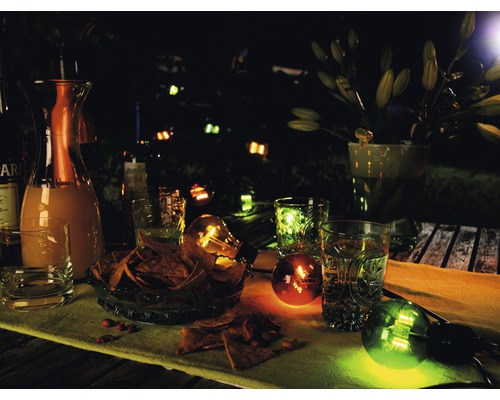 Trädgårdsscen på kvällen med drycker, snacks och dekorativ belysning.