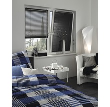 Sovrum med fönster, utrustat med svarta persienner för ljuskontroll.