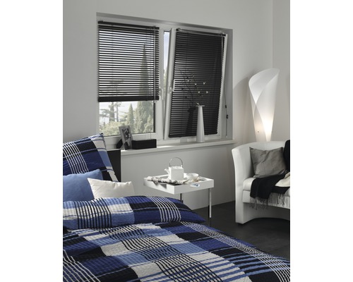 Sovrum med fönster, utrustat med svarta persienner för ljuskontroll.