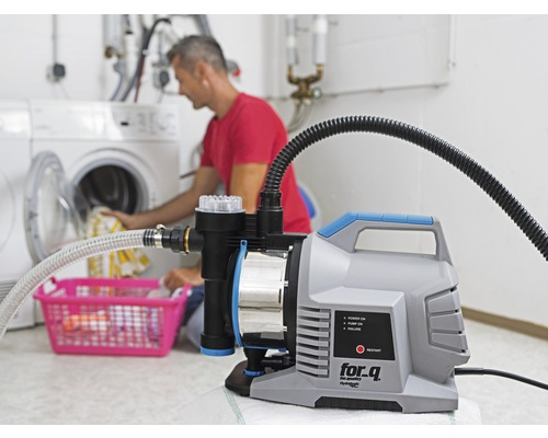 Hydroforpump i bruk i tvättstugan med en person som lägger tvätt i en tvättmaskin