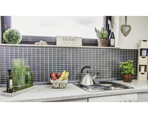 Köksscen med tillbehör och redskap på en bänkskiva framför en kakelvägg