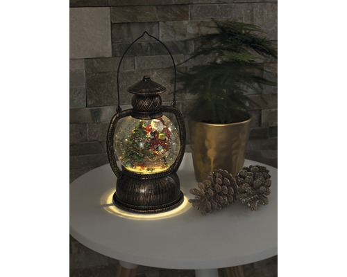 Dekorativ snöglobslykta med julmotiv och belysning.