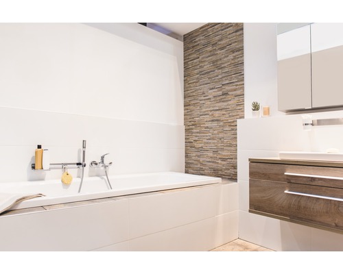 Ljust badrum med badkar, tvättställ och väggplattor