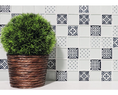 Dekorativ platta med mönster och konstgjord växt i flätad kruka