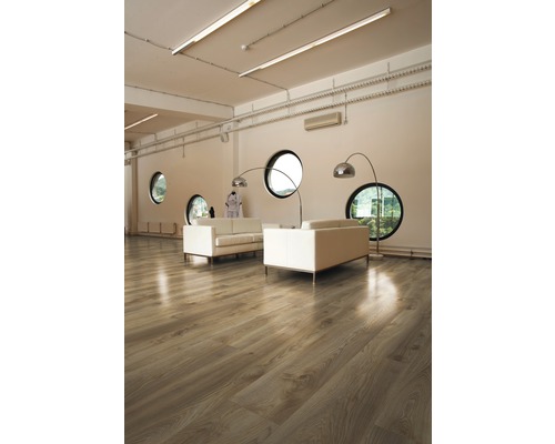 Ljust rum med trägolv, soffor och runda fönster.