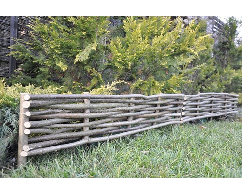 Dekorativ trädgårdsstaket av flätade grenar i trädgården