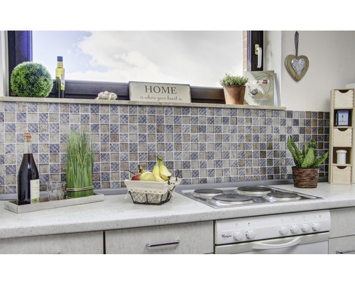 Köksscen med mosaikplattor, spis, dekorationer och matvaror på en bänkskiva.