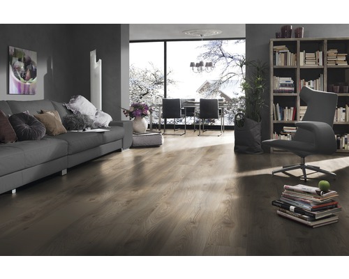 Vardagsrum med soffa, fåtölj, bokhylla och laminatgolv.