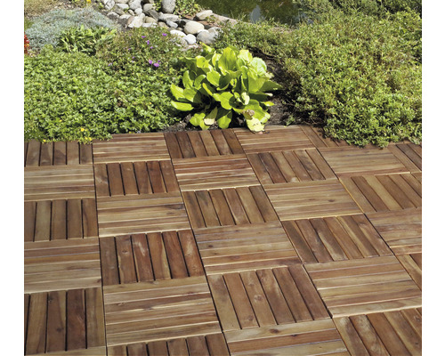 Lagda träplattor i trädgården bredvid växter och en damm