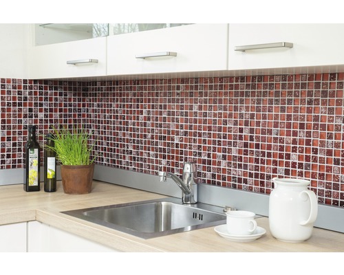 Köksscen med mosaikplattor, diskho och köksredskap på bänkskivan.