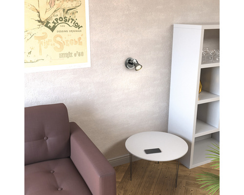 Vardagsrum med fåtölj, bord, hylla och vägglampa