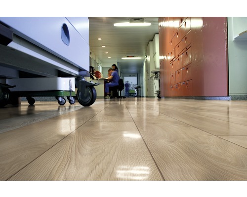 Ljust trägolv i en sjukhuskorridor med medicinsk utrustning och personal