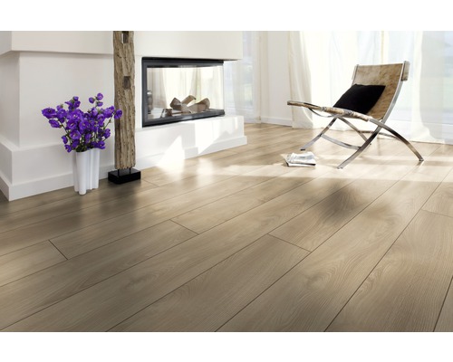 Ljust rum med laminatgolv, öppen spis och fåtölj