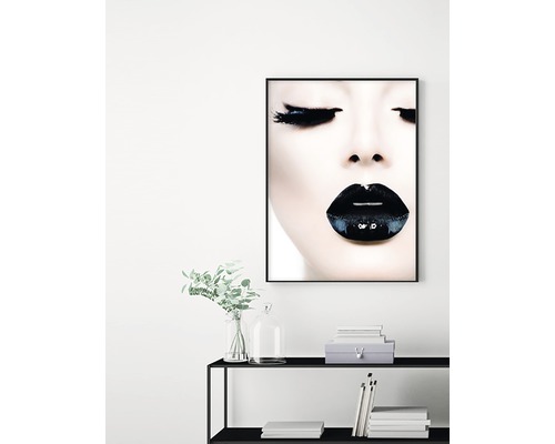 Dekorativ väggkonst med ett porträtt av en kvinna med mörkt läppstift ovanför en svart hylla