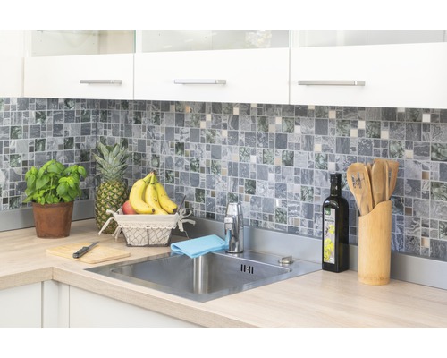 Ljust kök med mosaikplattor, diskho i rostfritt stål och färska ingredienser.