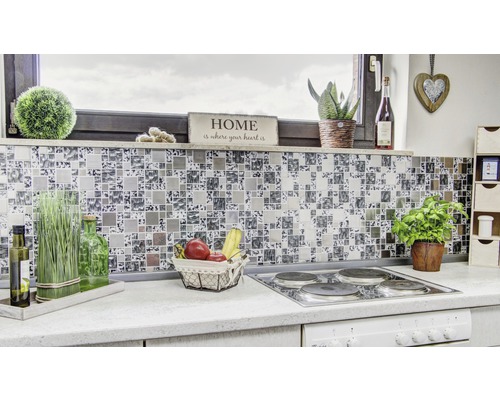 Detaljbild av ett modernt kök med mosaikplattor som stänkskydd, spis och diverse dekorationer.