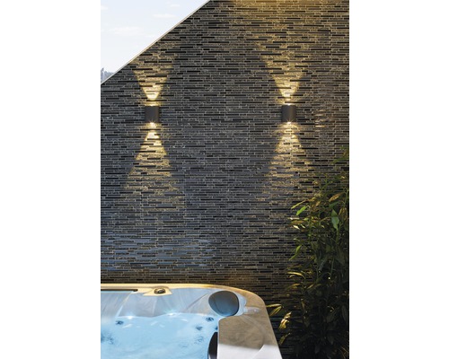 Två utomhuslampor på en stenmur bredvid en bubbelpool