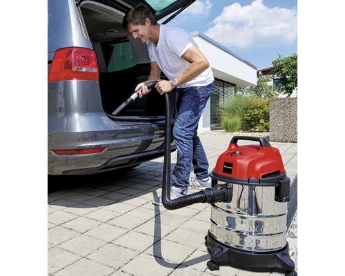 Man dammsuger bagageutrymmet på en bil med en våt- och torrdammsugare