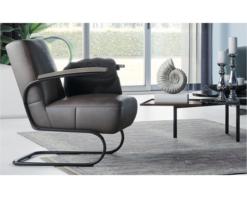 Vardagsrumsscen med brun läderfåtölj, kudde, sidobord och dekoration