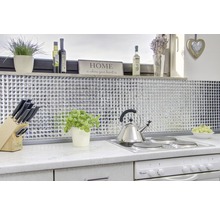 Ljust kök med mosaikplattor, kokplatta, vattenkokare och dekorativa element.