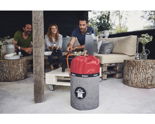 Scen med en gasflaska med lock och tre personer som grillar utomhus