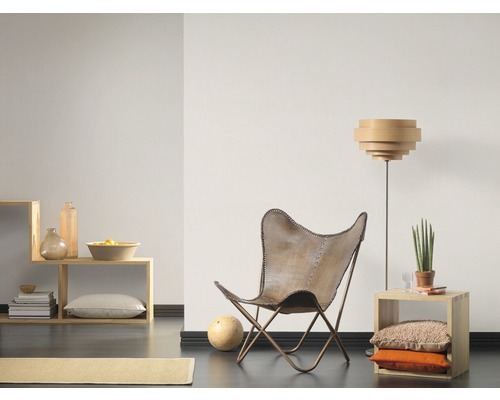 Vardagsrum med fåtölj, golvlampa och trähylla