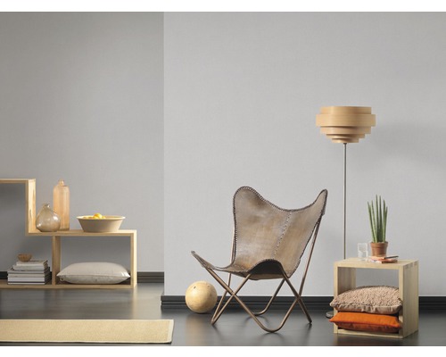 Vardagsrum med fåtölj, golvlampa och trähyllor